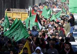 A Palestinian militant holds up a weapon as others wave Hamas flags during the funeral of Mohammed Ali in the East Jerusalem refugee camp of Shuafat, in an area Israel annexed to Jerusalem after capturing it in the 1967 Middle East war, January 5, 2016. Ali was shot dead by Israeli police on October 10, 2015, after he stabbed two Israeli police officers, seriously wounding one of them, near Damascus Gate, outside Jerusalem's Old City, Israeli police spokesman Micky Rosenfeld said. REUTERS/Ammar Awad  - GF10000283058